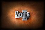 The word vote made from vintage lead letterpress type on a leather background.