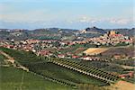 View of hills with green vineyards and small town of Roddi on background in Piedmont, Northern Italy.