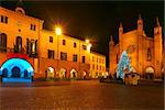 Illuminated and decorated Christmas Tree on central square between city hall and San Lorenzo cathedral at evening in Alba, Italy.