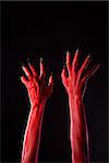 Red demonic hands with black nails, Halloween theme, studio shot on black background