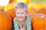 cute smiling boy having fun at the pumpkin patch