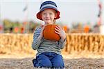 adorable smiling boy holding pumpkin at the pumpkin patch
