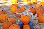 cute positive boy having fun and being silly at the pumpkin patch