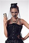 sensual blonde girl with halloween style and make-up wearing gothic dress and dark veil on the face and taking smartphone in the hand