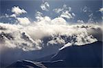 Evening mountain in haze and sunlight clouds. View from ski resort Gudauri. Caucasus Mountains, Georgia.