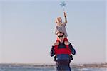 cute smiling boy and his young father playing with pinwheel outside