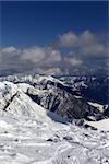 Sunlit mountains in clouds, view from off-piste slope. Caucasus Mountains, Georgia, ski resort Gudauri.