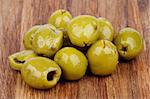 Heap of Delicious Pickled Green Olives with Spices and Olive Oil closeup on Wooden background