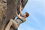 young healthy man rock climbing or bouldering outdoors