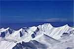 Snowy mountains at sunny day and multicolor blue sky. Caucasus Mountains, Georgia, ski resort Gudauri.