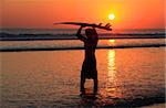 Silhouettes of surfer at red sunset. Kuta beach. Bali