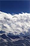 Winter mountains with clouds and silhouette of parachutist. Caucasus Mountains. Georgia, view from ski resort Gudauri.