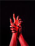 Red demonic hands with black nails, Halloween theme, isolated on black background