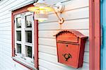 Red mail box, window and lamp on a white wooden house