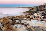 Botany Bay Australia at first light dawn (before sunrise) with beautiful multi coloured sandstone rocks and boulders in the foreground and the pink and blue sky hues reflected in it's serene waters.  Botany Bay was the bay of Captain James Cook's first landing   Long exposure, bracketed