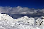 Ski slope and beautiful snowy mountains in clouds. Caucasus Mountains, Georgia. Ski resort Gudauri.