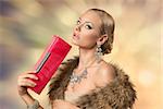 luxury fashion portrait of very sensual blonde girl with aristocratic look posing with fur collar, bright jewellery and elegant small bag in the hand