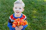 positive smiling boy holding beautiful flowers at spring time