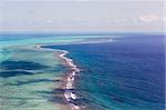 aerial view of the barrier reef of the coast of San Pedro, Belize. with large waves breaking away from the coast