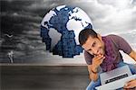 Composite image of thoughtful man sitting on floor using laptop and smiling at camera