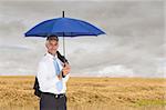 Composite image of mature businessman holding blue umbrella