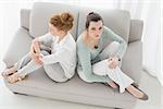 High angle view of unhappy young female friends not talking after argument at home on the couch