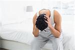 Young man suffering from headache in bed at home