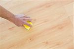 Close-up of a hand with sponge cleaning the parquet floor at home