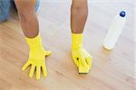 Close-up of yellow gloved hands with sponge cleaning the floor at home