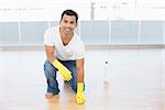 Portrait a smiling young man cleaning the parquet floor at house