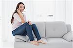 Portrait of a relaxed happy young woman using cellphone on sofa in living room at home