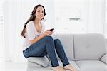 Portrait of a relaxed young woman text messaging on sofa in living room at home