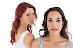Unhappy young female friends not talking after argument over white background