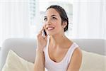 Relaxed young woman using cellphone on sofa in living room at home