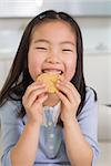 Portrait of a smiling young girl enjoying cookies in a bright home