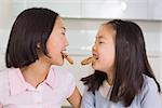 Two cheerful young girls enjoying cookies in the kitchen