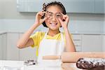 Portrait of a smiling young girl holding cookie molds in the kitchen at home