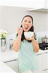 Portrait of a young woman eating salad in the kitchen at home