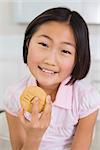 Portrait of a smiling young girl enjoying cookie in a bright home