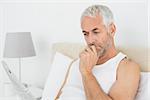 Casual mature man reading newspaper in bed at home