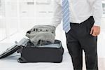 Mid section of a businessman unpacking luggage at a hotel bedroom