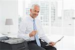 Portrait of a mature businessman with coffee cup reading newspaper by luggage at a hotel room