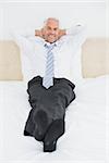 Full length portrait of a relaxed mature businessman sitting in bed at home