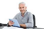 Portrait of a mature businessman with digital tablet and telephone at desk against white background