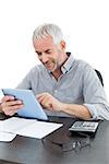 Mature businessman with digital tablet and calculator at desk against white background