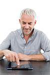 Smiling mature businessman using digital tablet at desk against white background