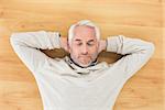 Overhead view of a mature man sleeping on parquet floor at home