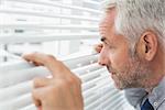 Extreme close-up side view of a serious mature businessman peeking in the office