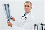 Portrait of a serious male doctor with x-ray picture of spine in the medical office