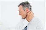 Close-up side view of a mature man suffering from neck pain over white background